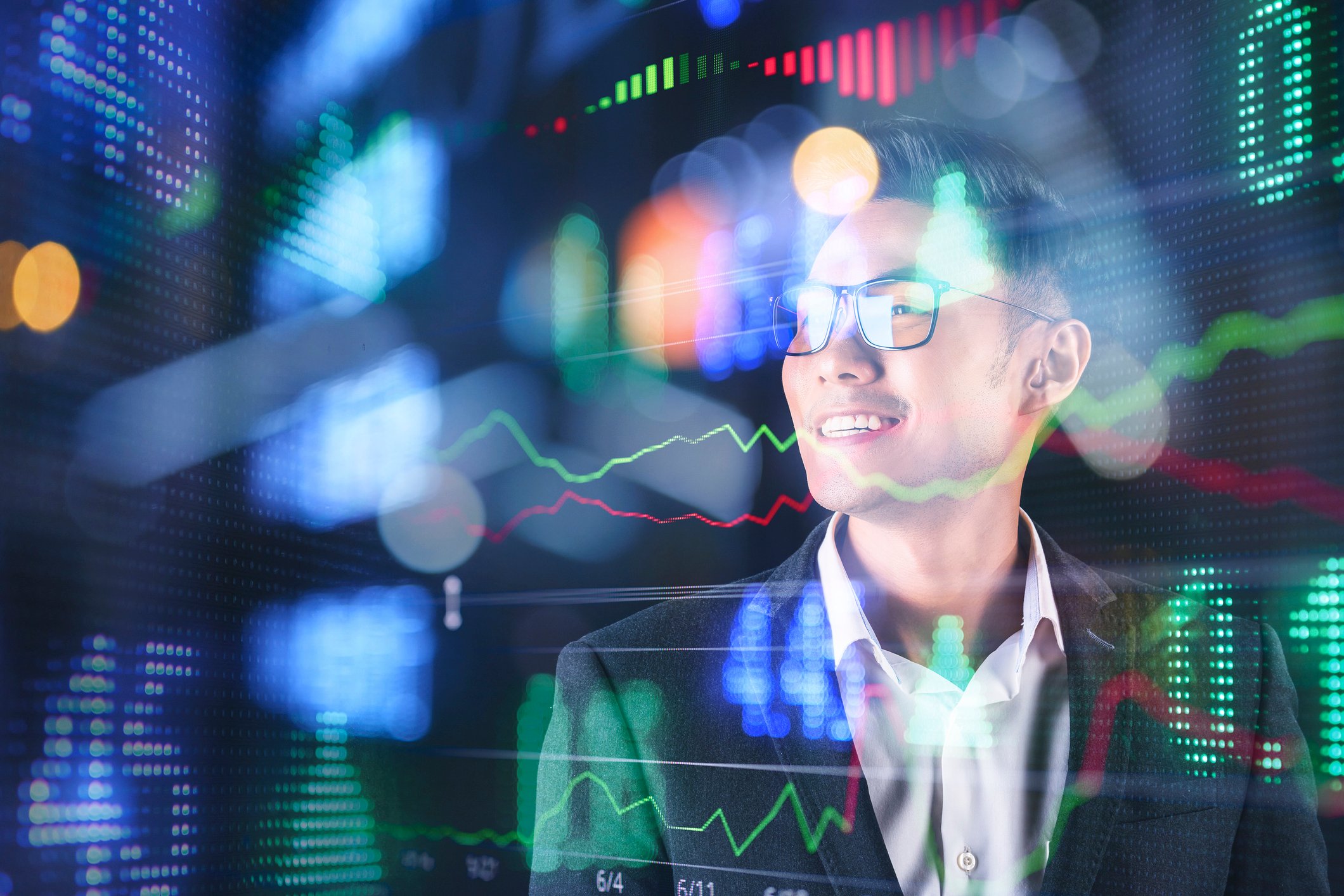 Person looking at glass wall with stock charts and quotes.
