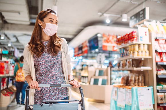 A woman with a mask on shopping in a grocery store.