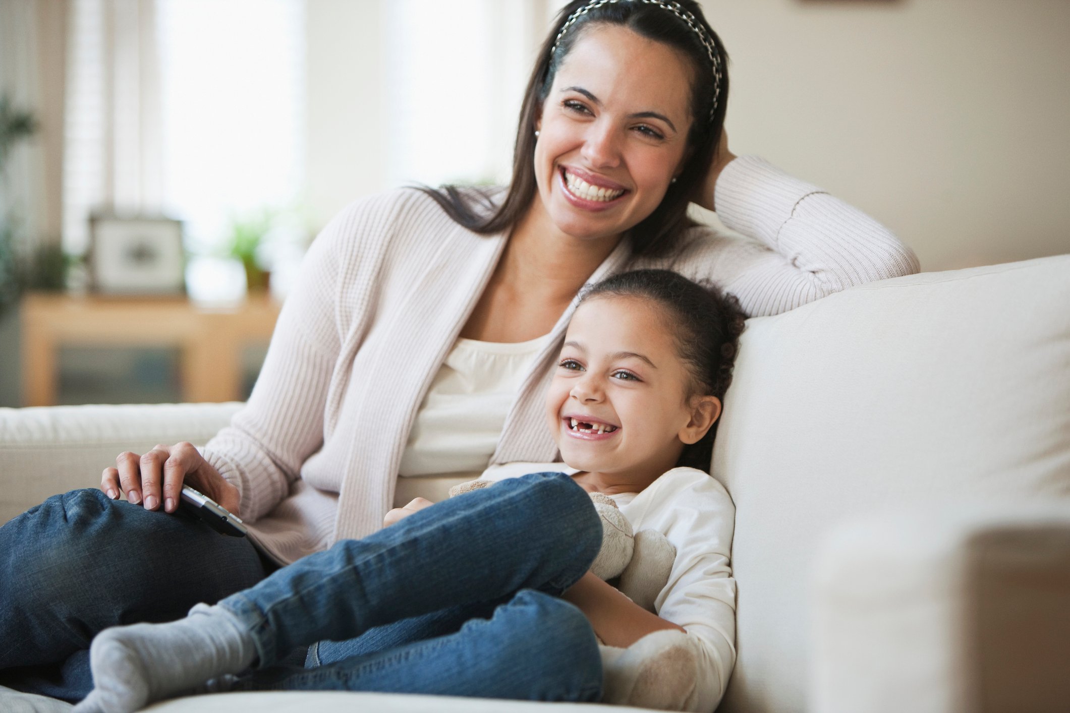 Mother and daughter smiling while sitting on couch