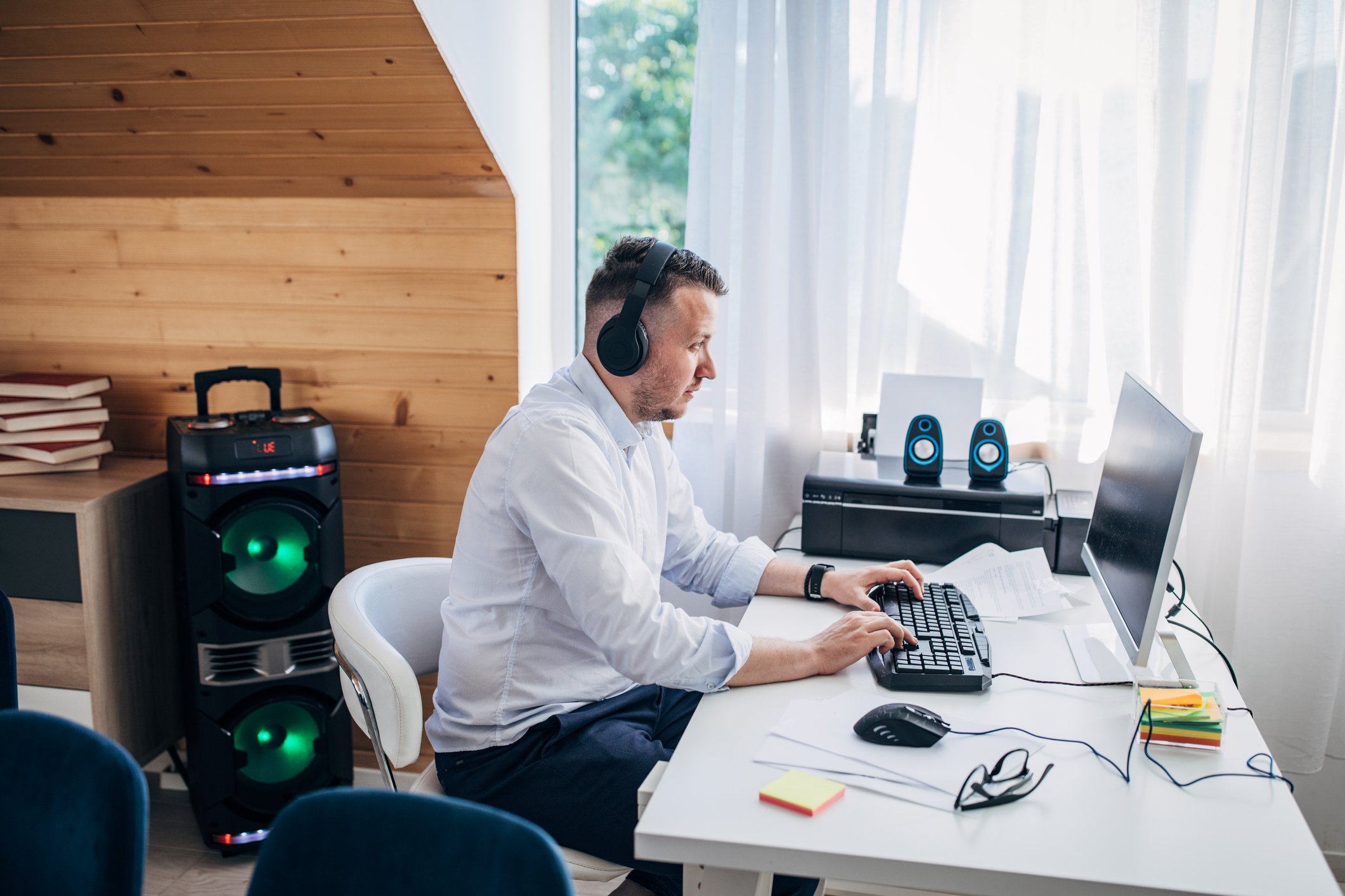 A remote worker wearing a headset and typing on a keyboard at home.