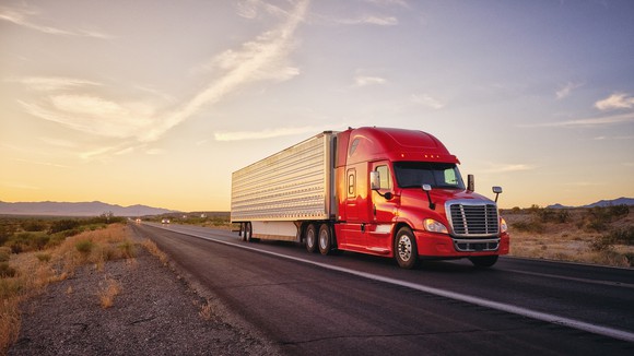 A heavy duty truck hauls cargo down a desert highway. 