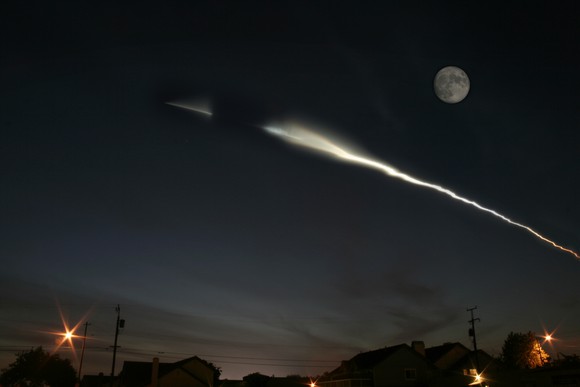 A rocket launch at night, seen from the ground.