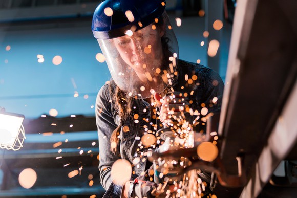 A person using an angle grinding tool in a workshop. 
