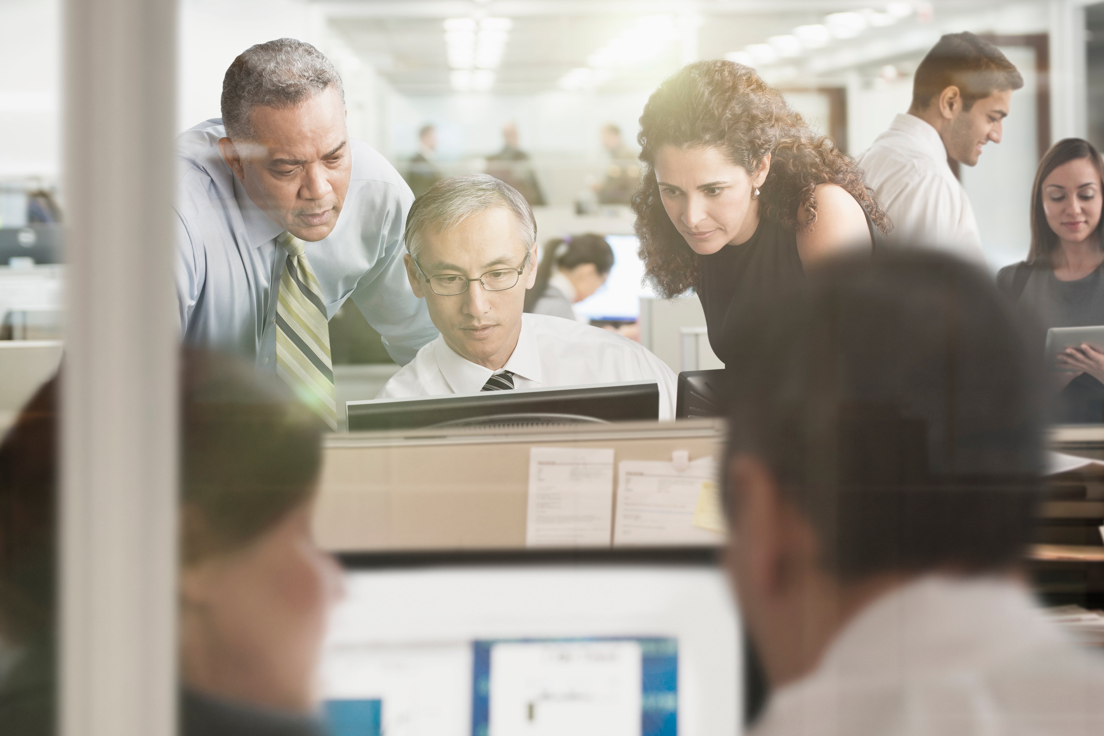 Financial professionals gather around a computer screen.