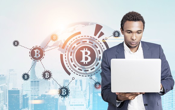 Man wearing a sportscoat looking somberly at his laptop with Bitcoin symbols in the background