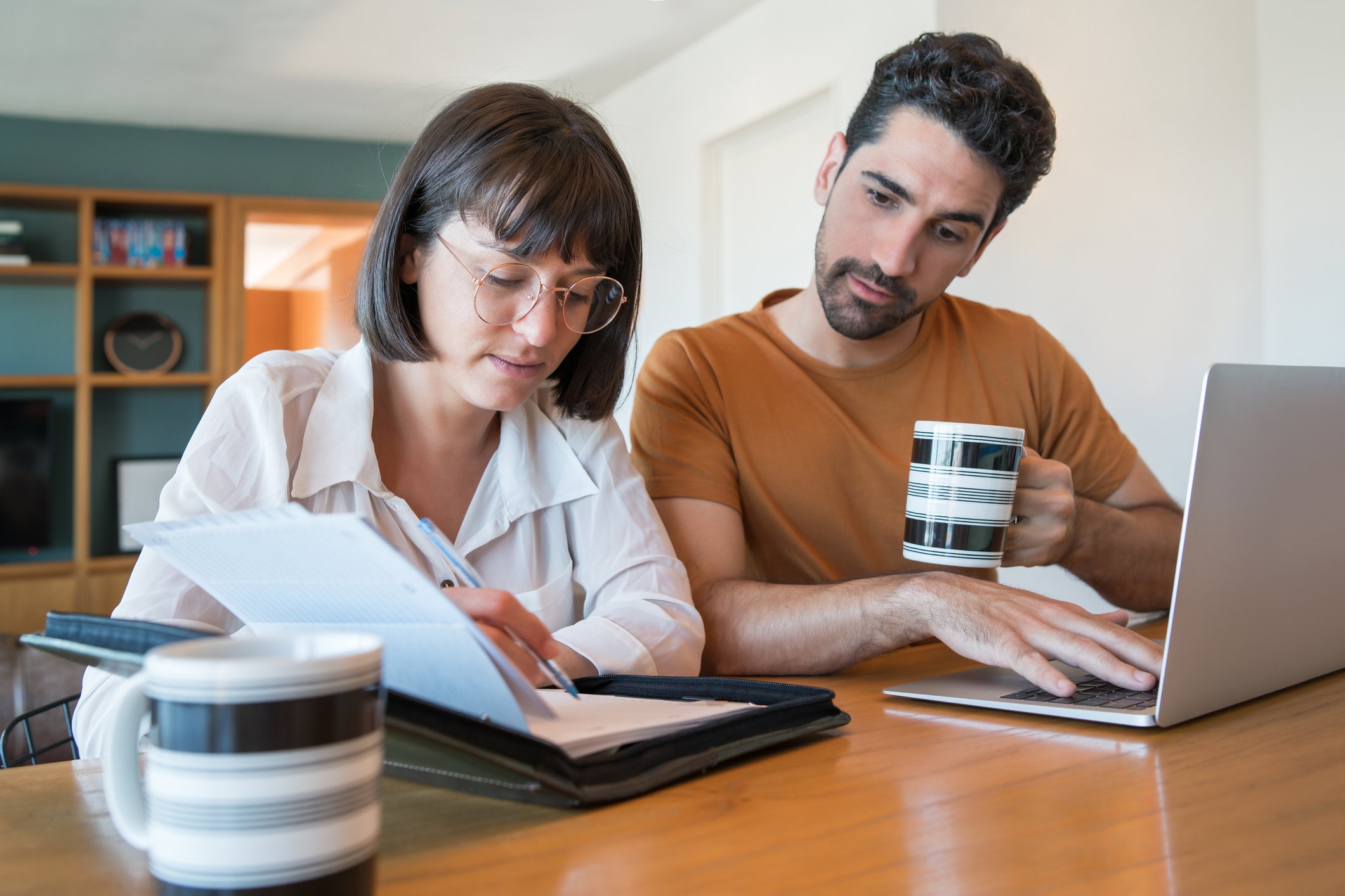 Man and woman using a laptop and reviewing documents.