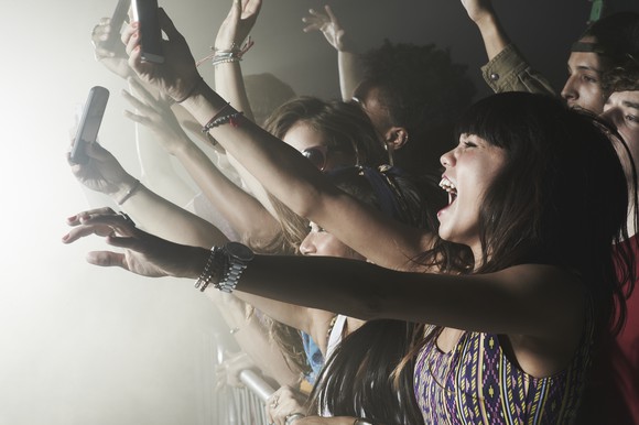 Cheering concertgoers record a performance on their mobile phones. 