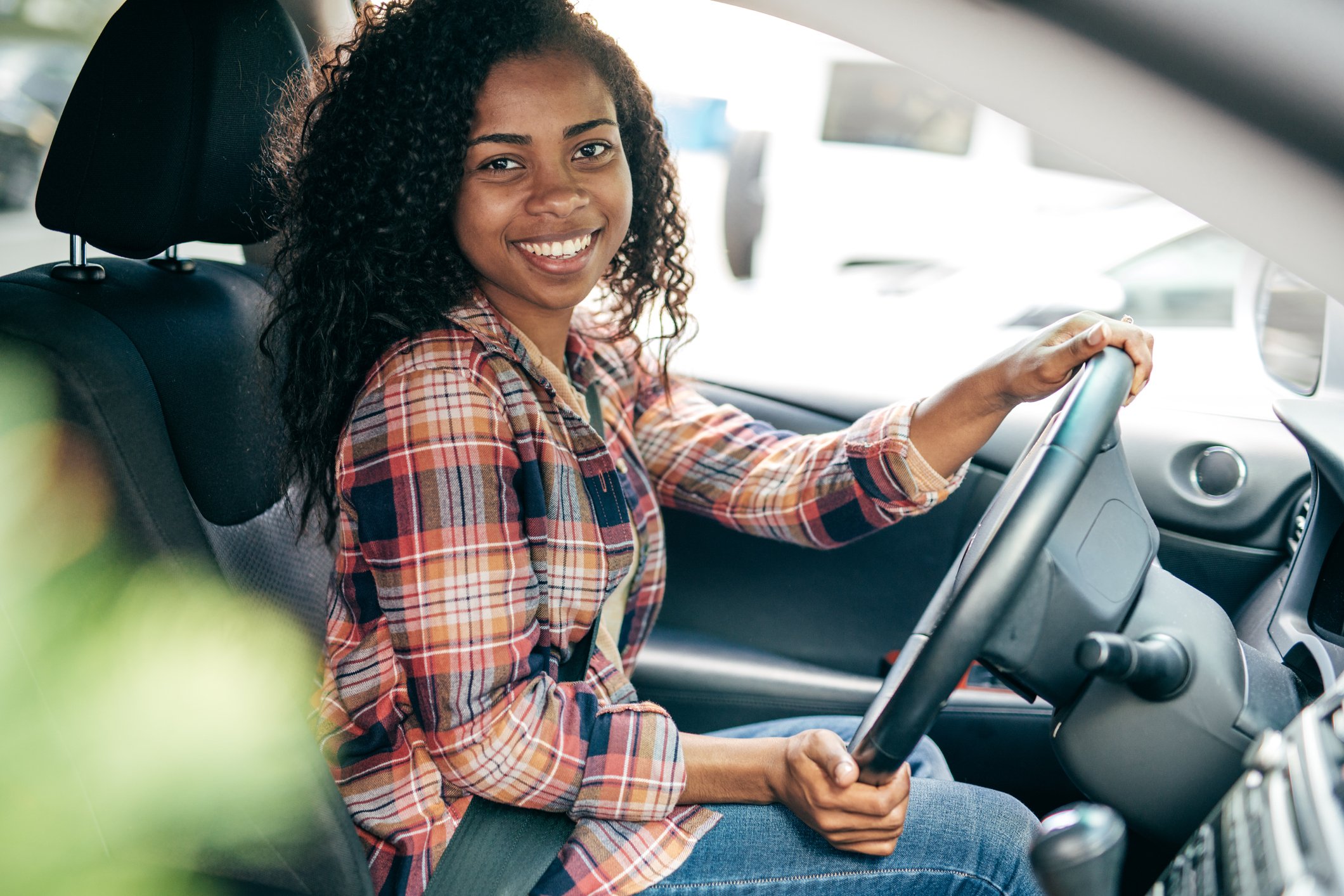 Smiling person sitting in the driver's seat of a car.