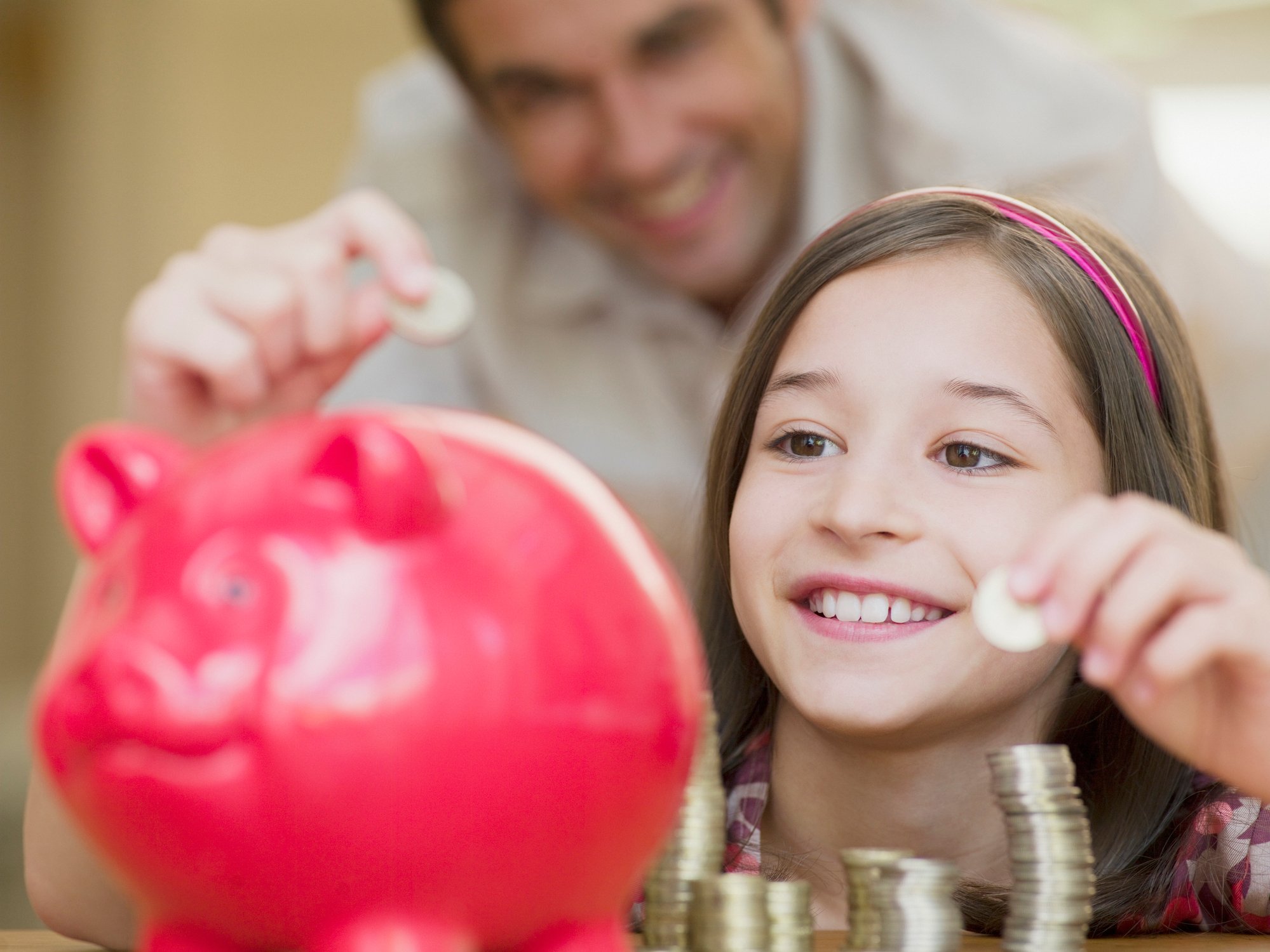 A child placing coins in a piggy bank.
