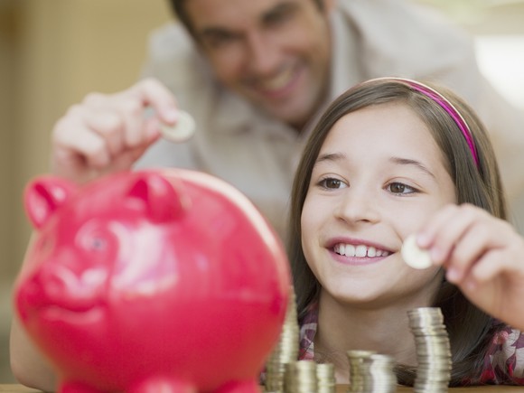 A child placing coins in a piggy bank.