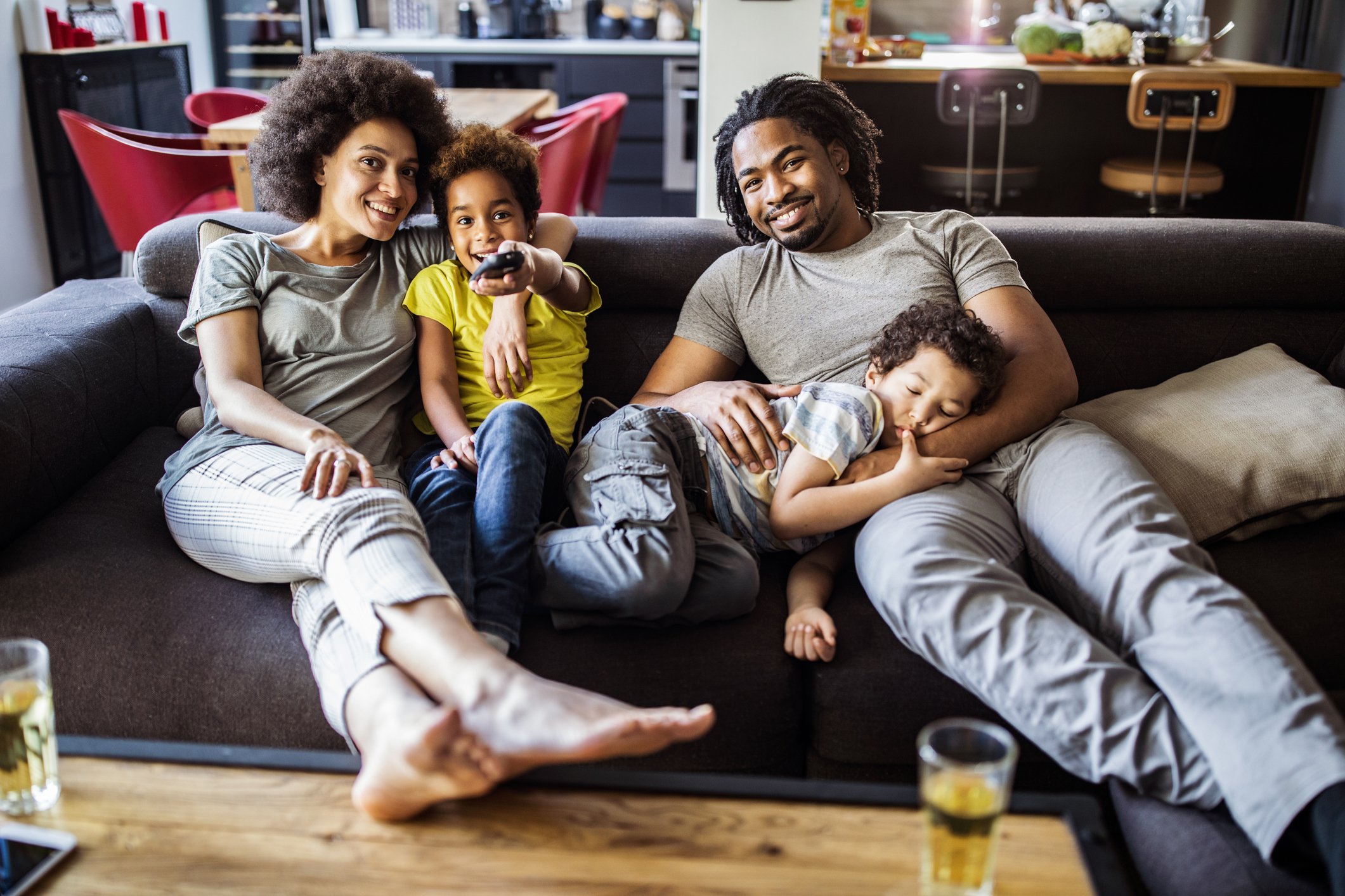 family of four on couch watching streaming television. 