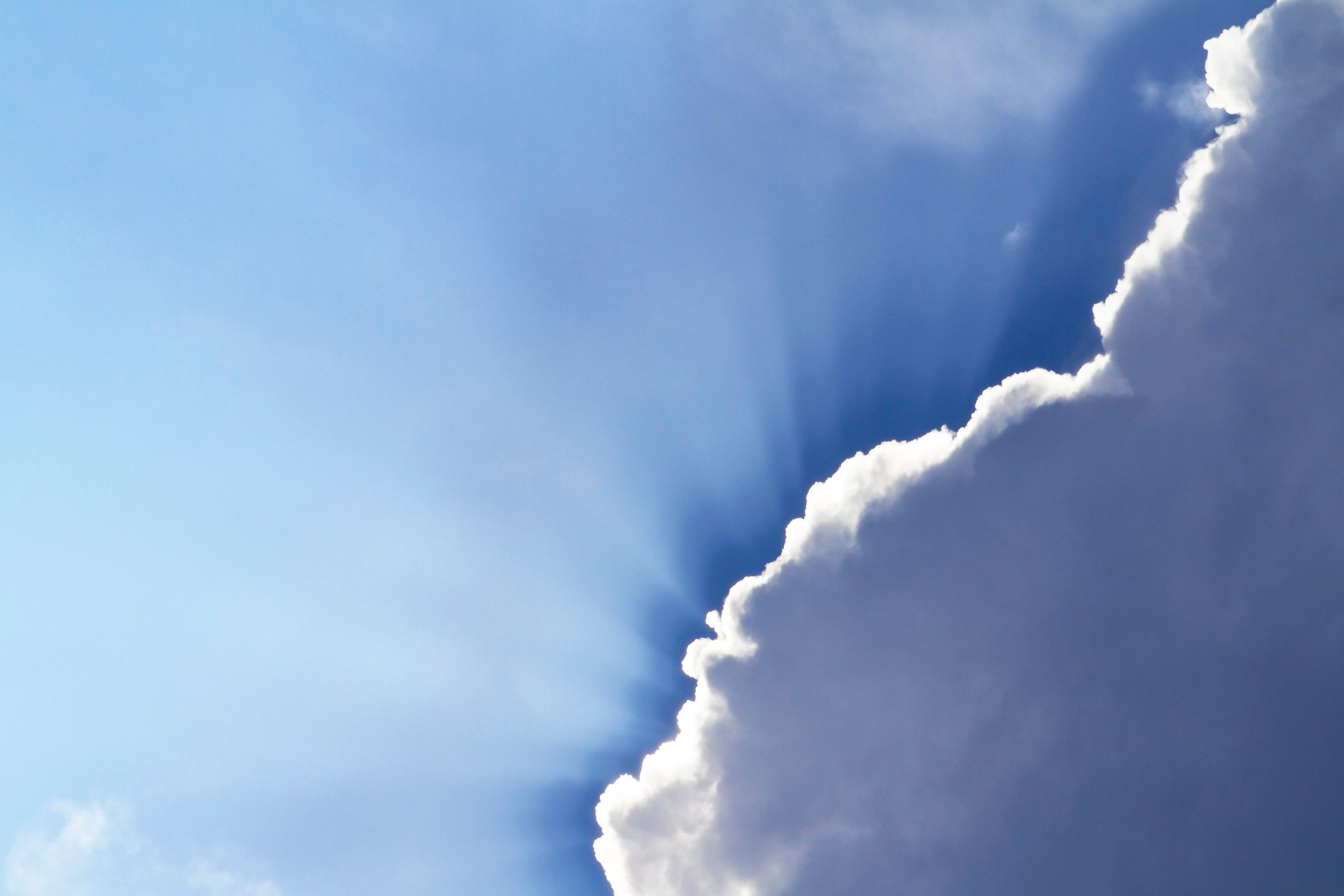 The sun peeks out behind some dark clouds.