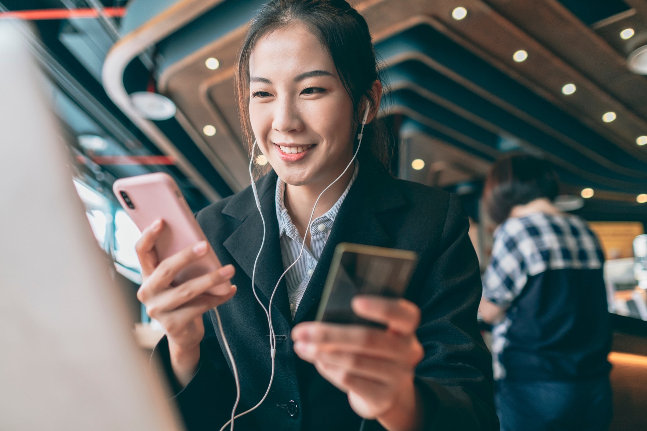 A young adult holding a smartphone and a credit card preparing to make a financial transaction.
