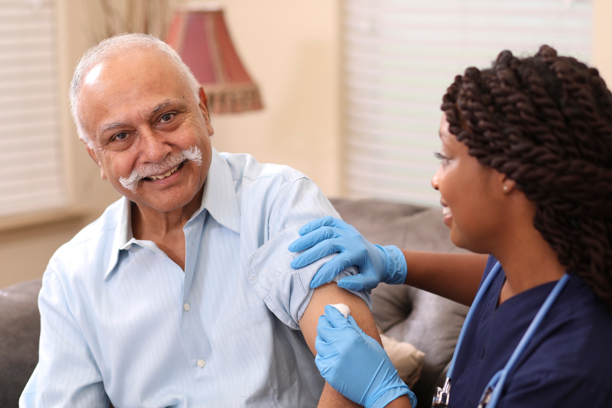 A healthcare worker vaccinating a smiling patient.