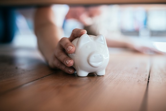 Someone finding a piggy bank under furniture.