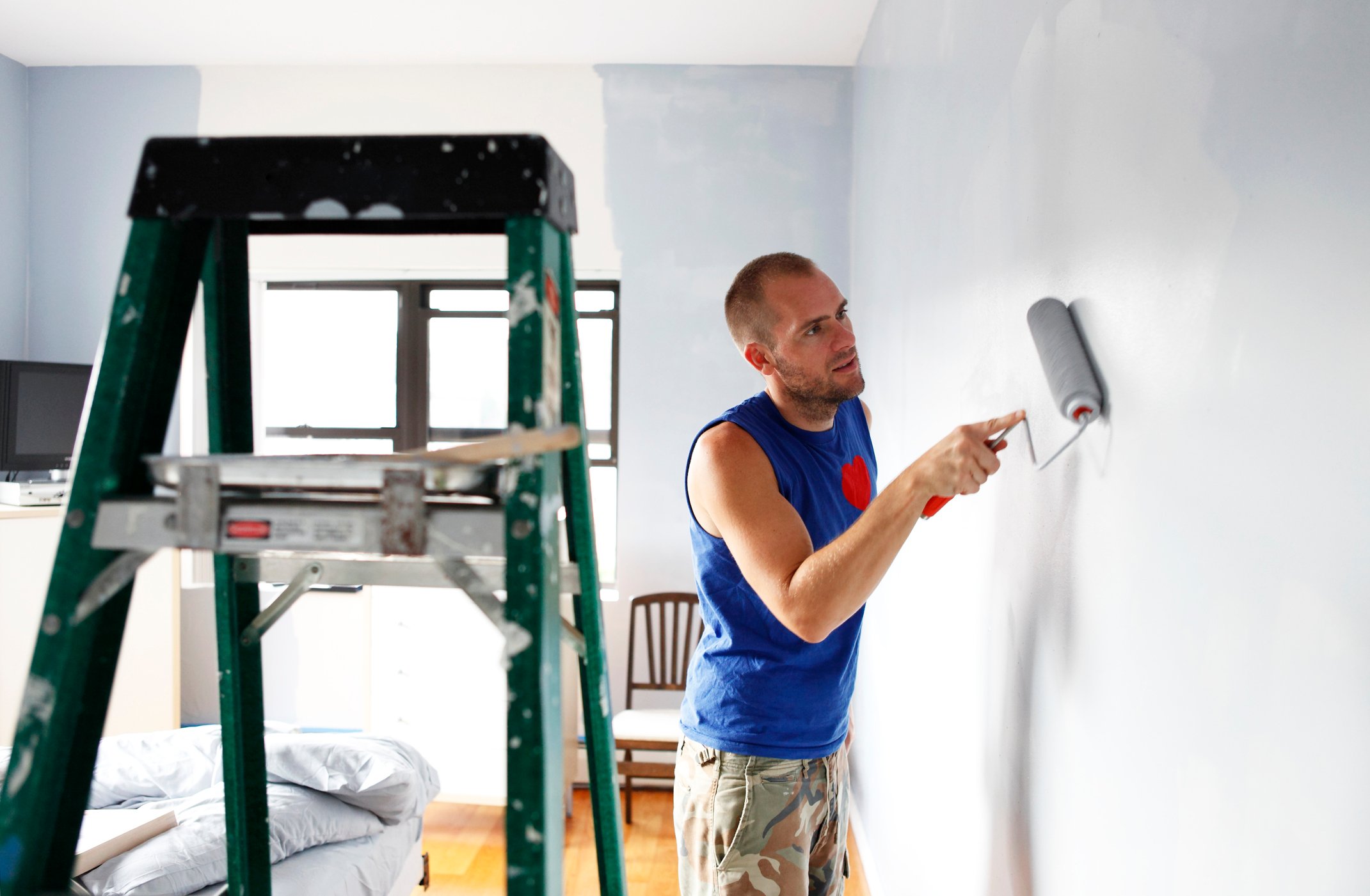 A man painting a bedroom.