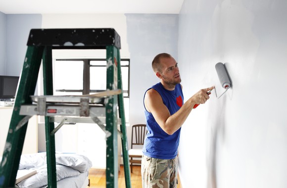 A man painting a bedroom.