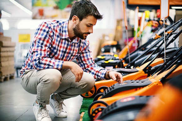 A man looking at a lawnmower.