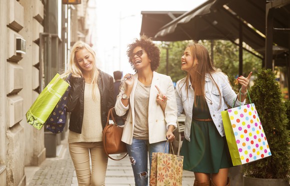 Three laughing women with shopping bags.