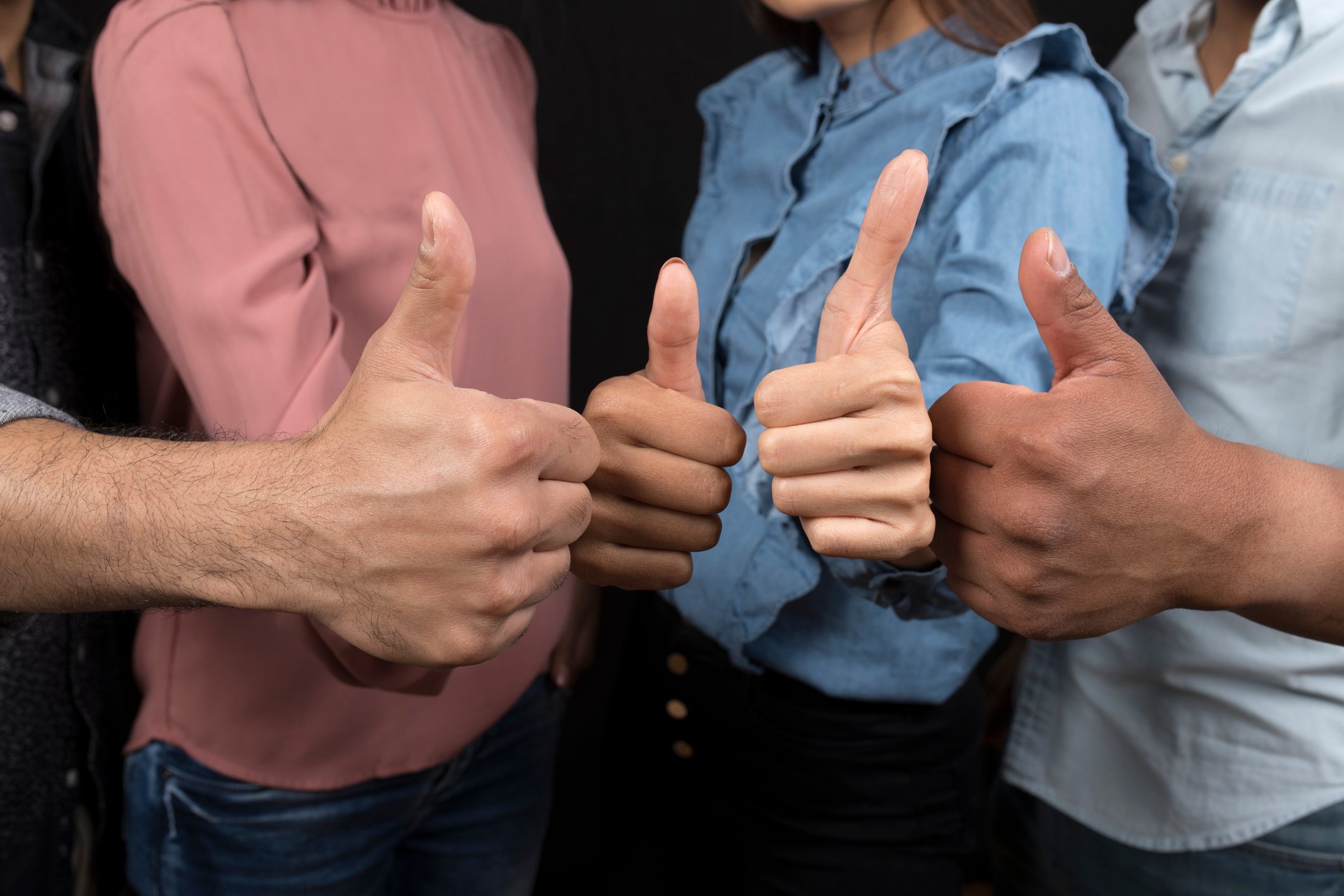 A group of four people holding their thumbs up.