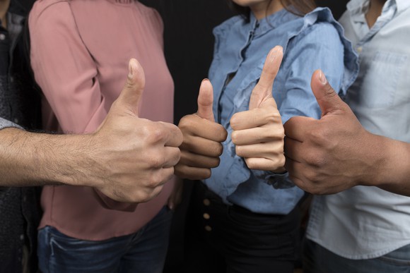 A group of four people holding their thumbs up.