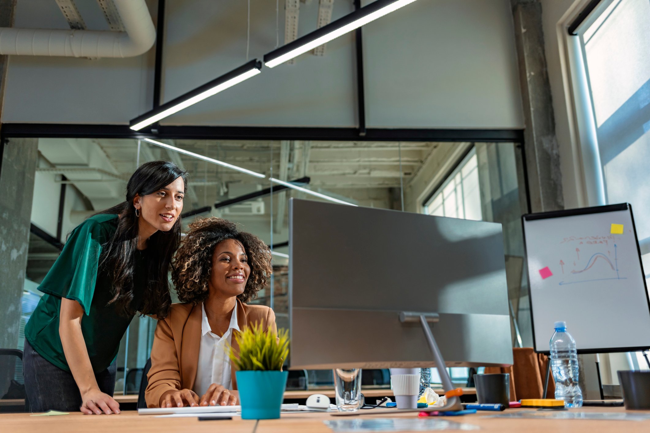 Two businesswomen working together on a computer.
