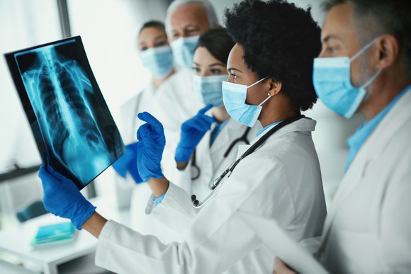 Team of doctors looks at the image of a chest X-ray.