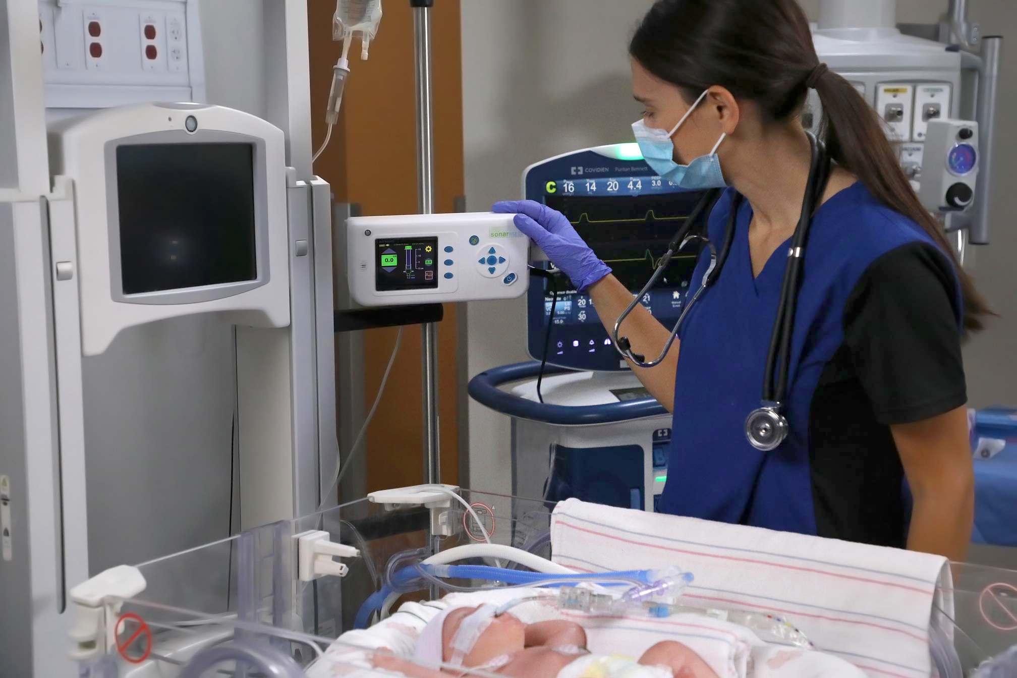 Healthcare professional next to an infant patient looking at Medtronic medical devices