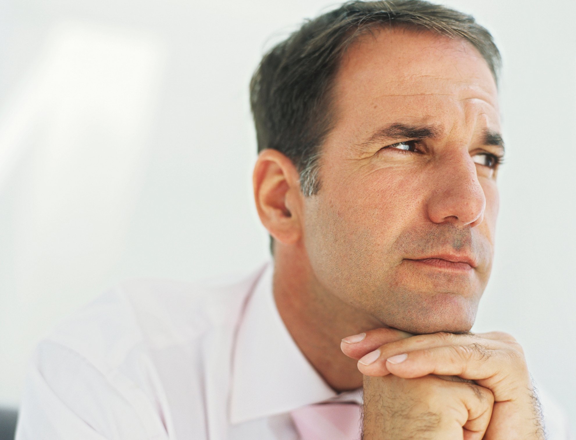 Man with his chin resting on his hands with a thoughtful expression on his face. 
