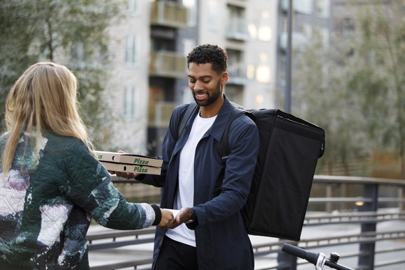 Man on a bicycle delivers pizza to a customer.