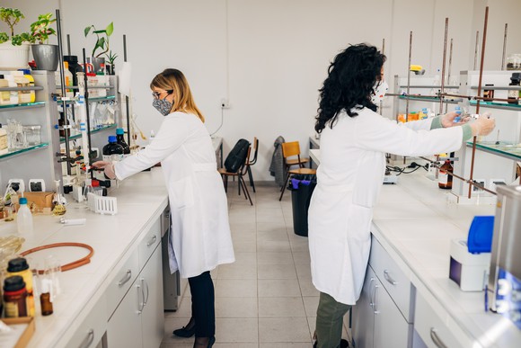 Two scientists stand working at separate laboratory benches.