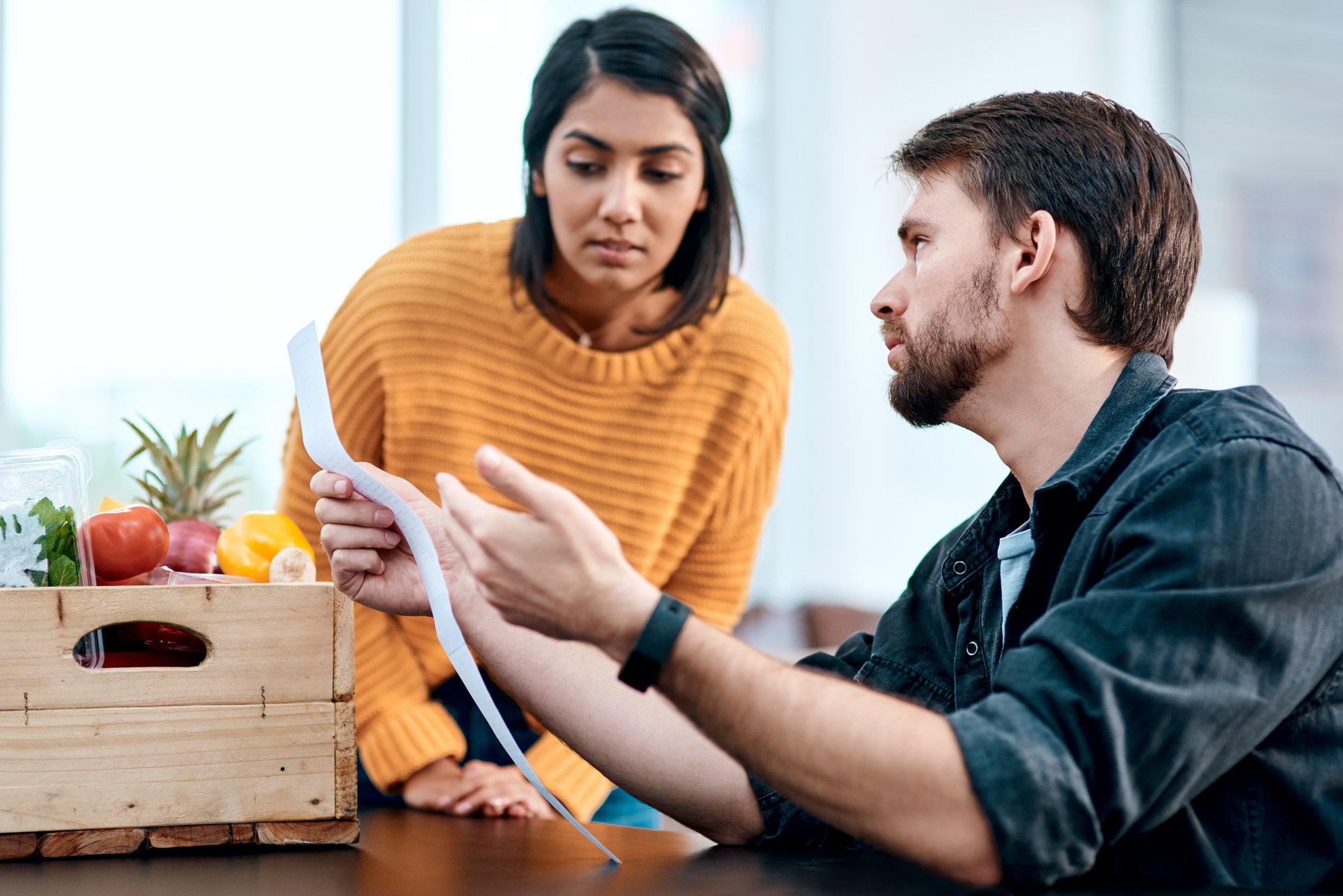 Two people with grocery box looking at receipt.