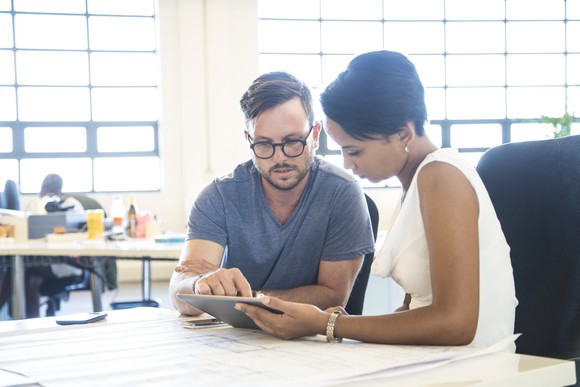 A man and a woman pointing at a tablet.