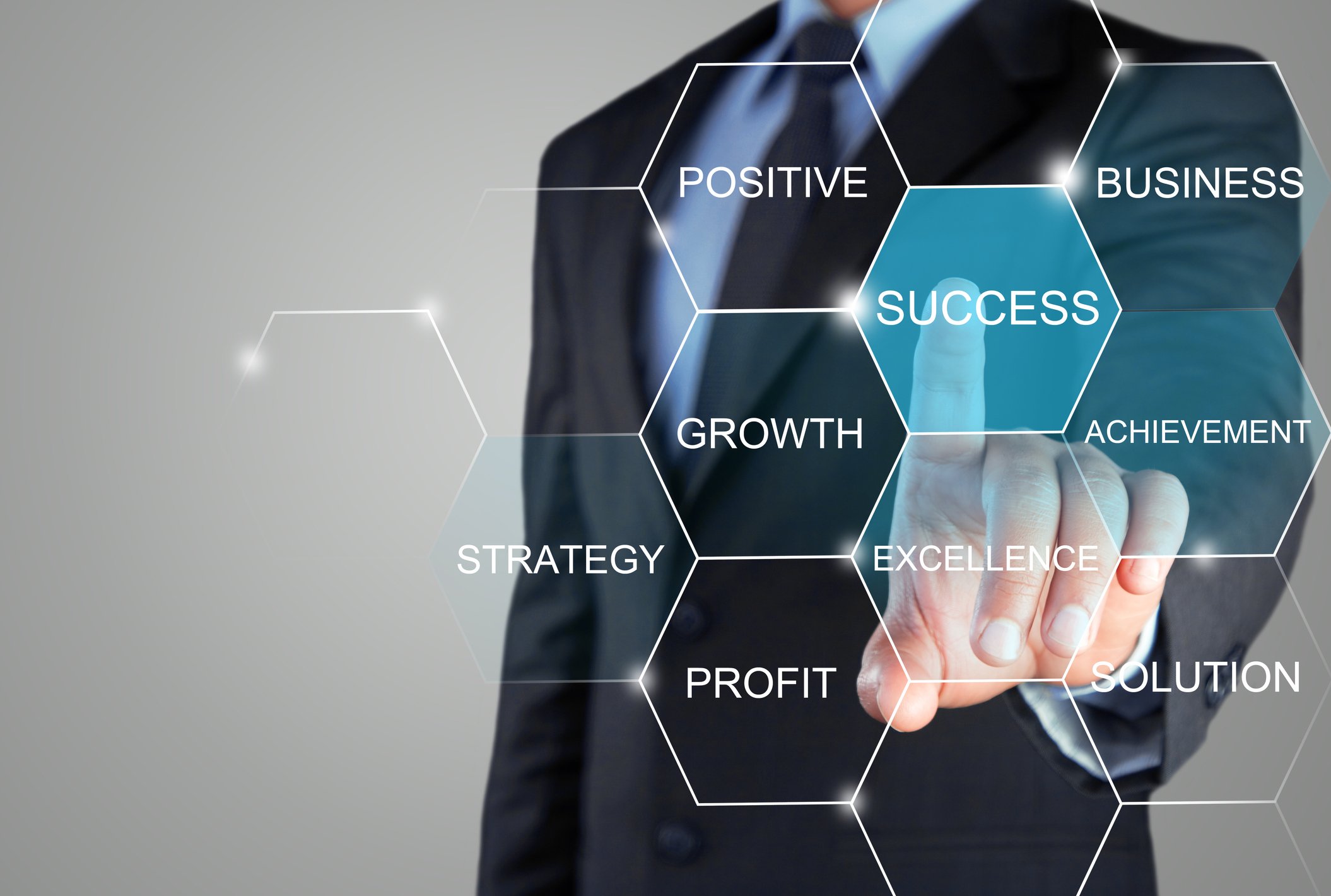 Businessman touching a six-sided digital button labeled success, one of several key terms in a cluster of buttons. 
