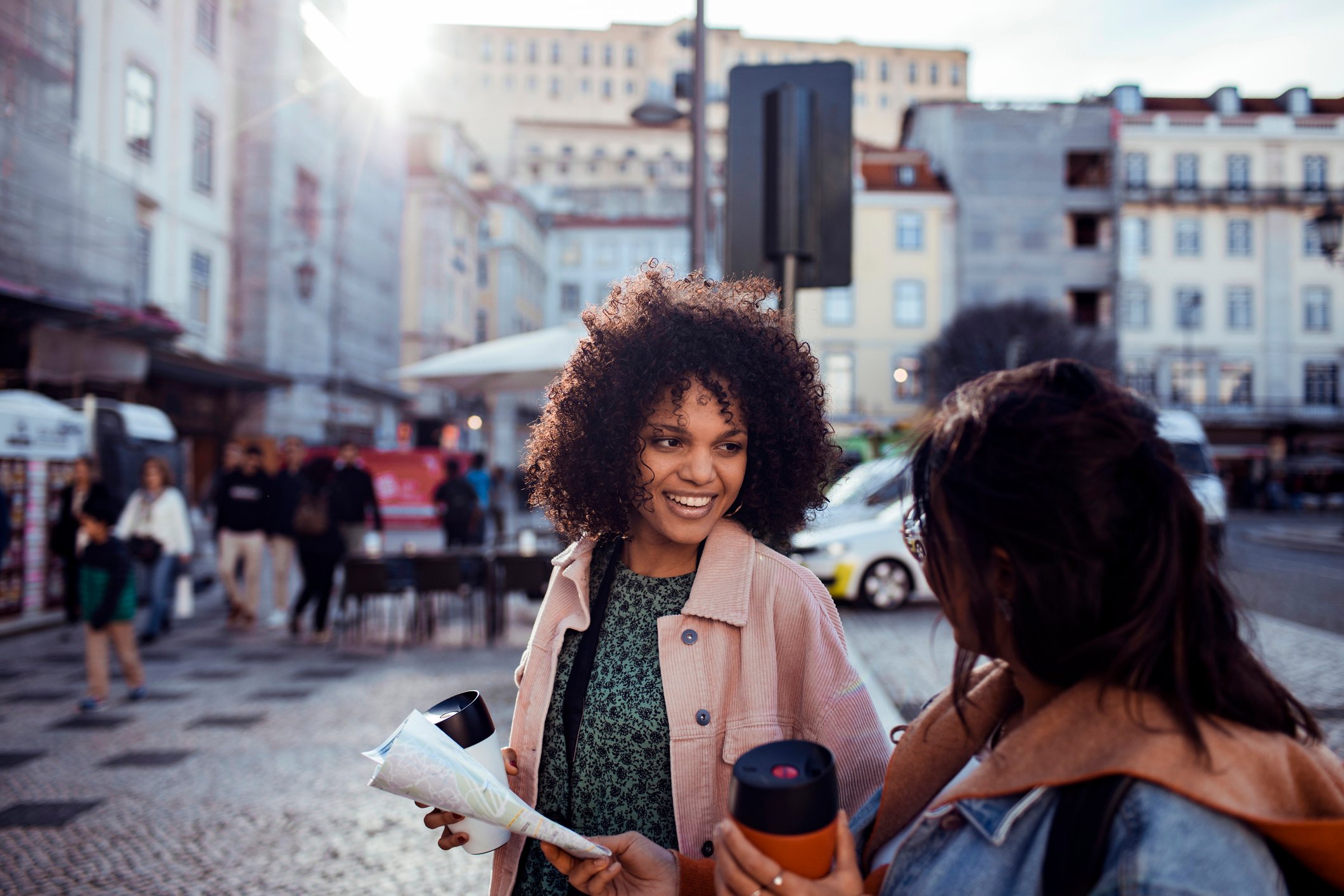 Smiling people with coffee in a town square.