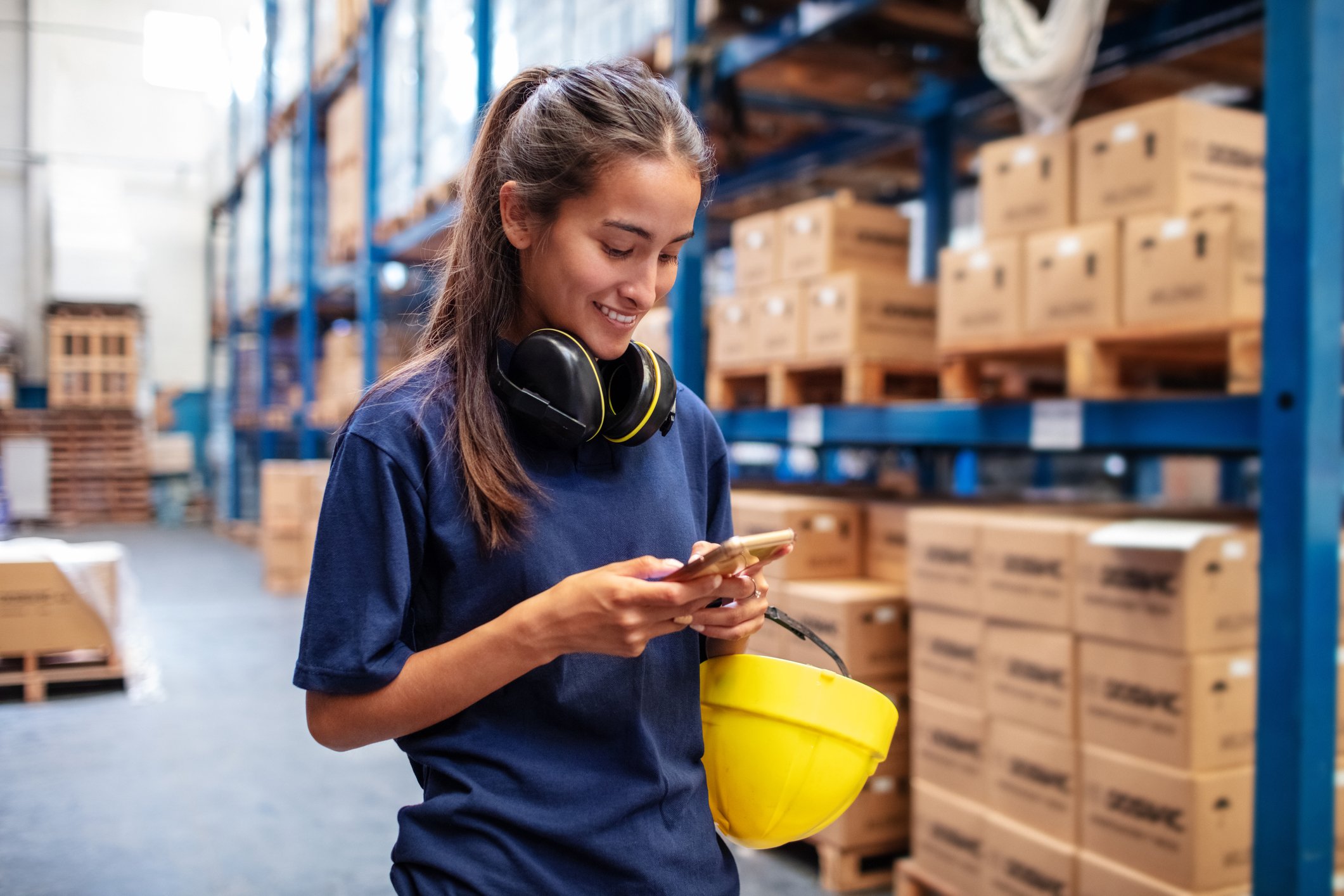 Warehouse worker checking investment account on mobile phone.