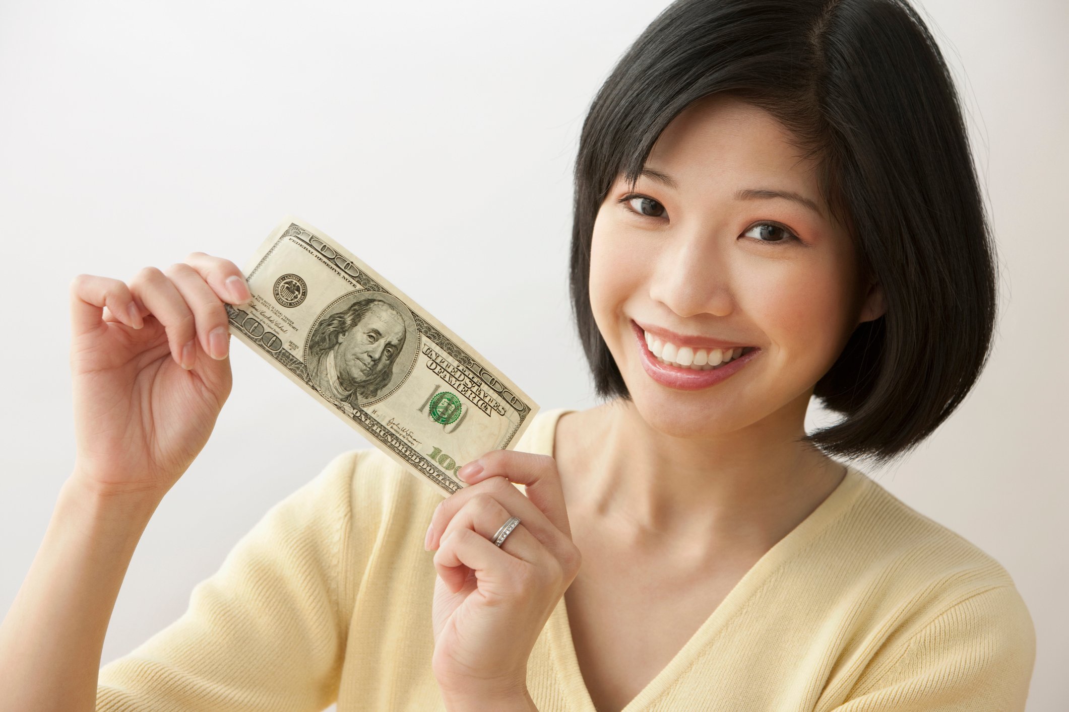 Smiling person holding a $100 bill