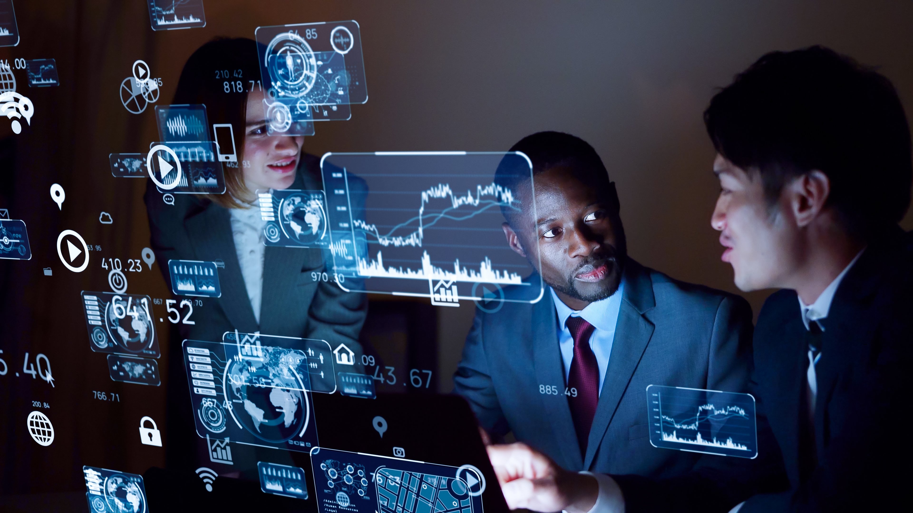 IT workers in front of an invisible screen with graphs on it. 