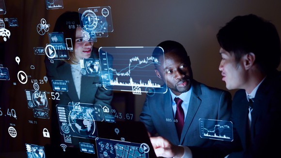 IT workers in front of an invisible screen with graphs on it. 