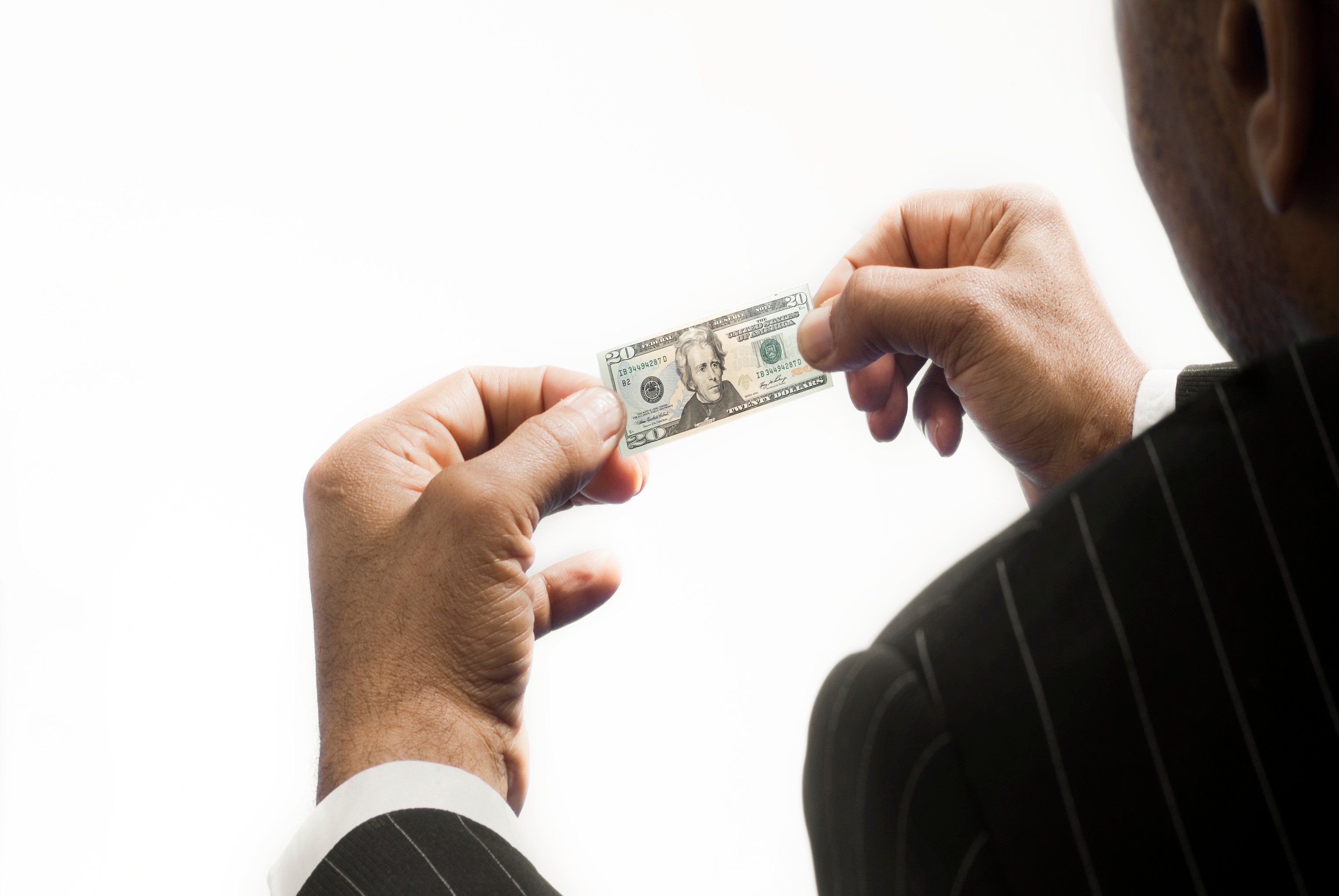 A person holding a miniature version of a $20 bill. 