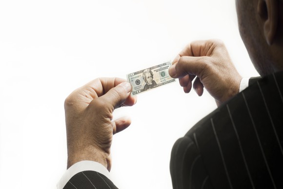 A person holding a miniature version of a $20 bill. 