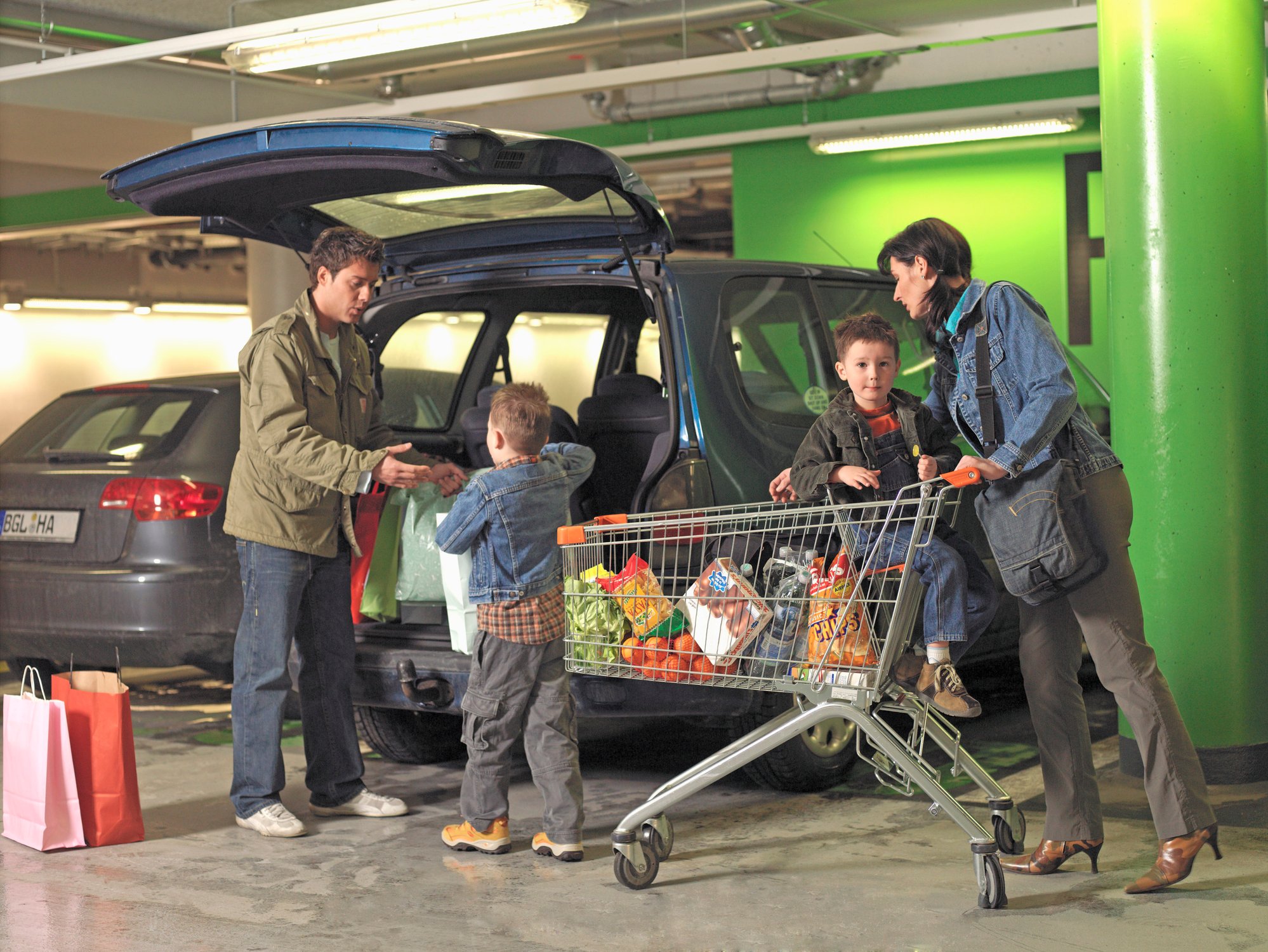A family taking a cart full of groceries to their car.