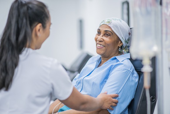 A doctor touches a patient's arm as she receives an infusion.