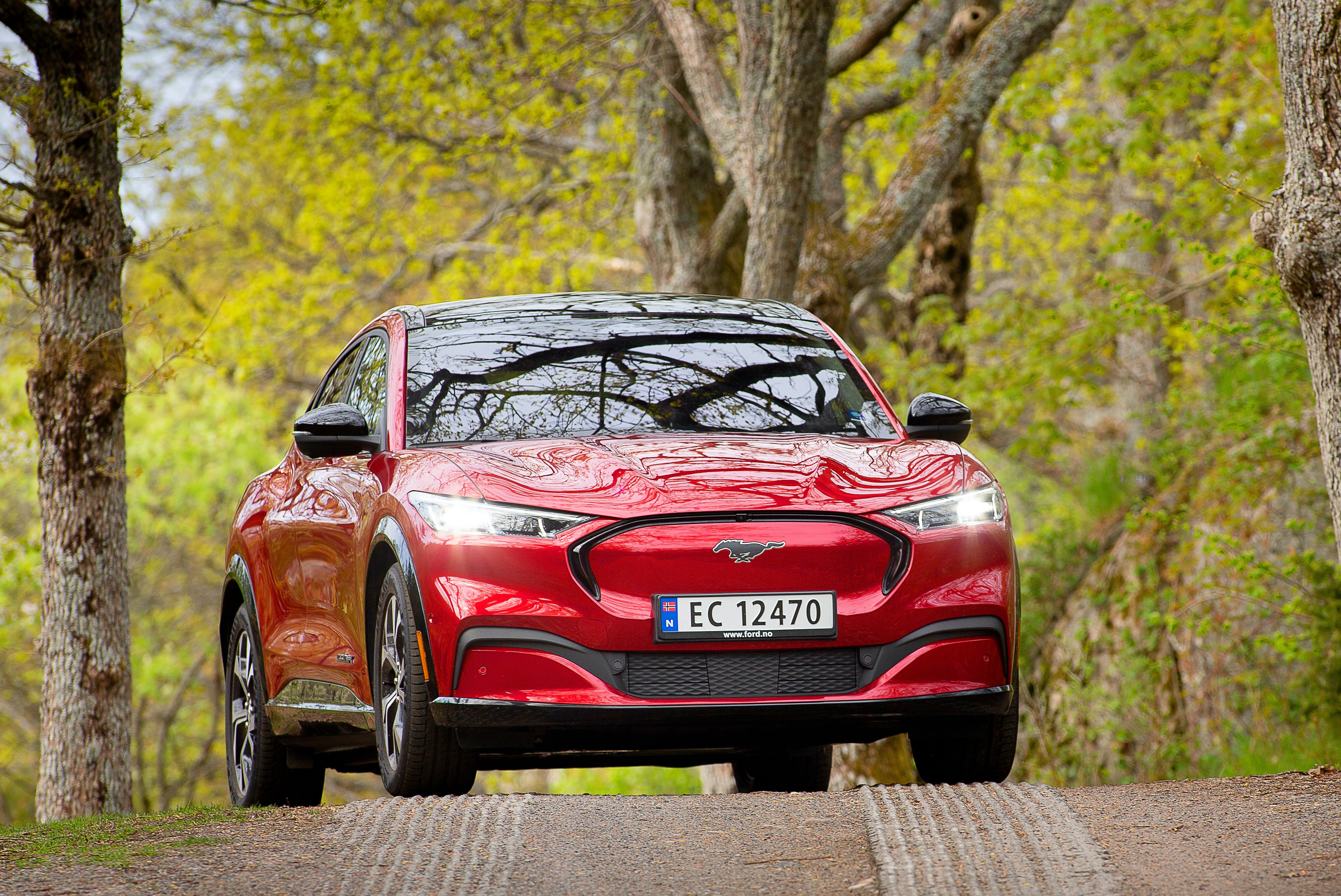 A red Ford Mustang Mach-E, a sporty electric crossover, with a Norwegian license plate. 