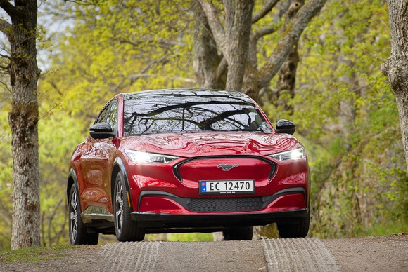 A red Ford Mustang Mach-E, a sporty electric crossover, with a Norwegian license plate. 