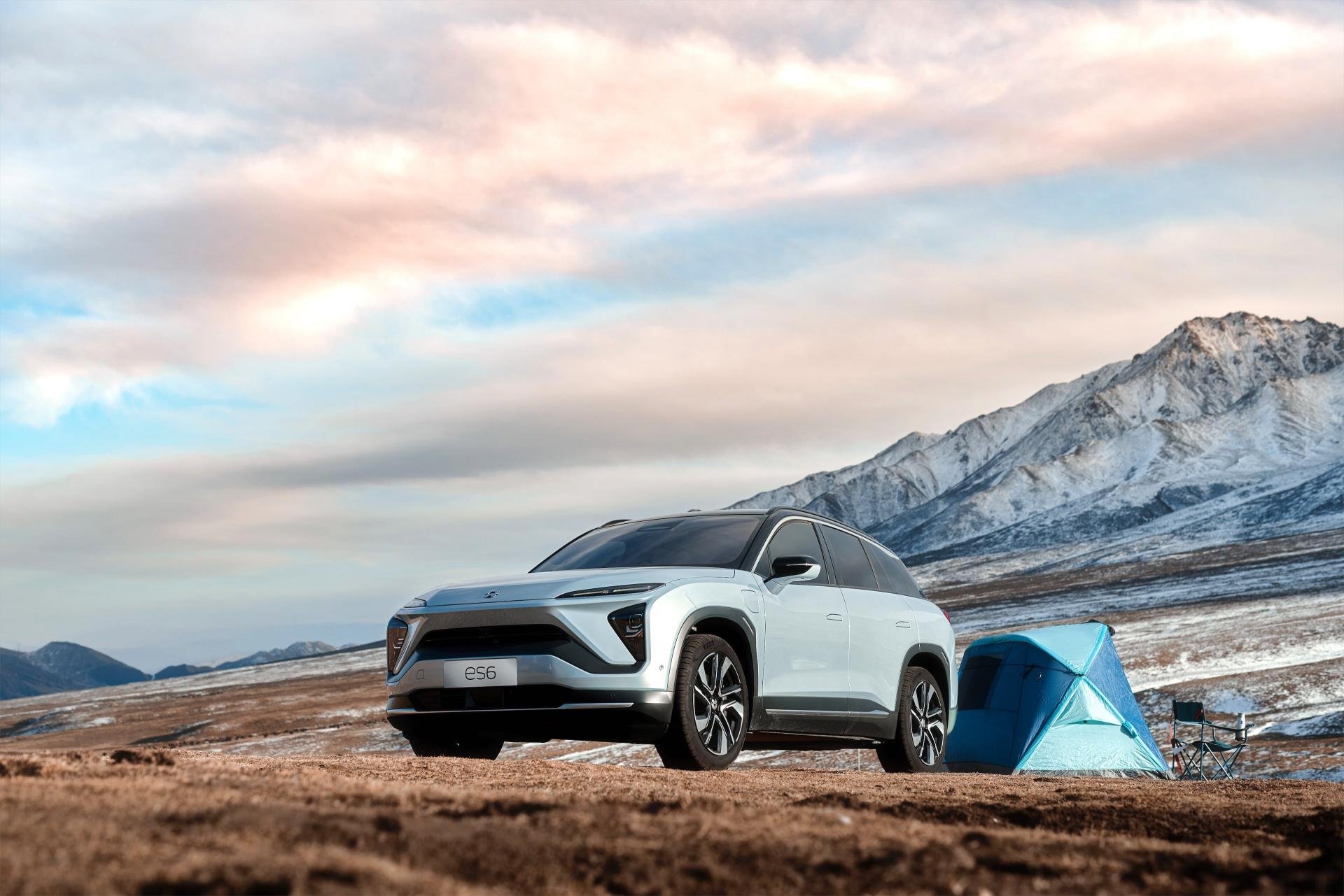A NIO ES6, an upscale five-passenger electric SUV, at a mountain campsite.