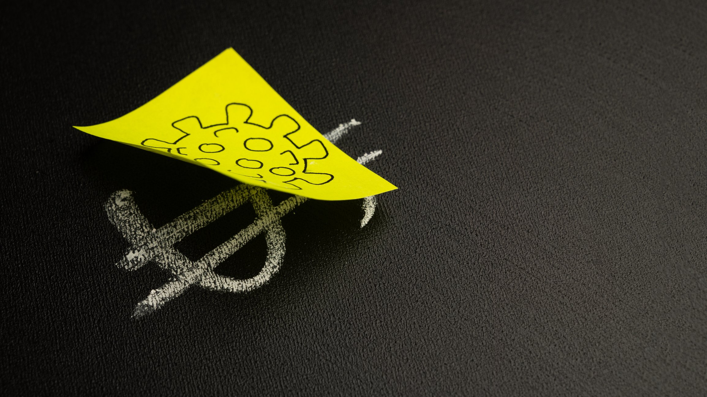 Yellow sticky note with a drawing of coronavirus over a chalkboard drawing of a dollar sign.