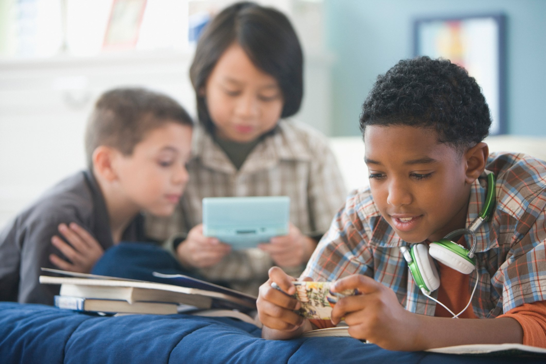Three kids playing games on mobile devices.