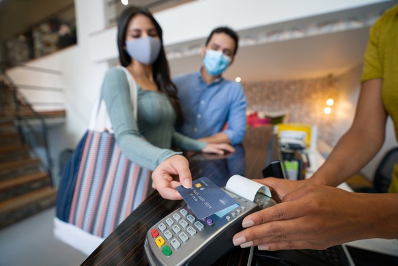 Masked shoppers use touchless card technology at checkout. 