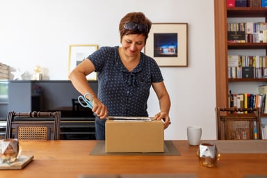 A person opening up a brown box on a table